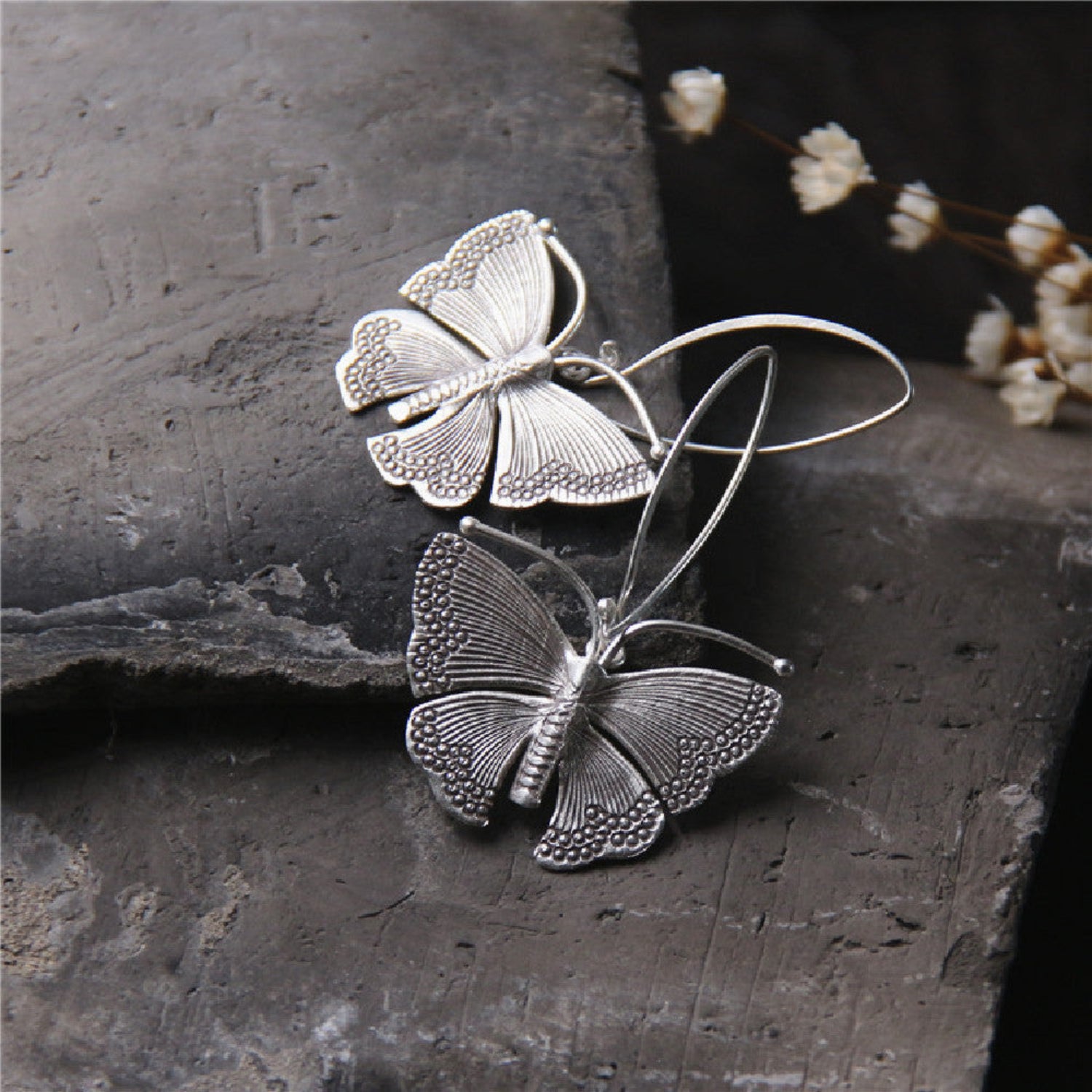 One pair Sterling silver moth earrings with detailed wings hanging from silver French hook ear wires.