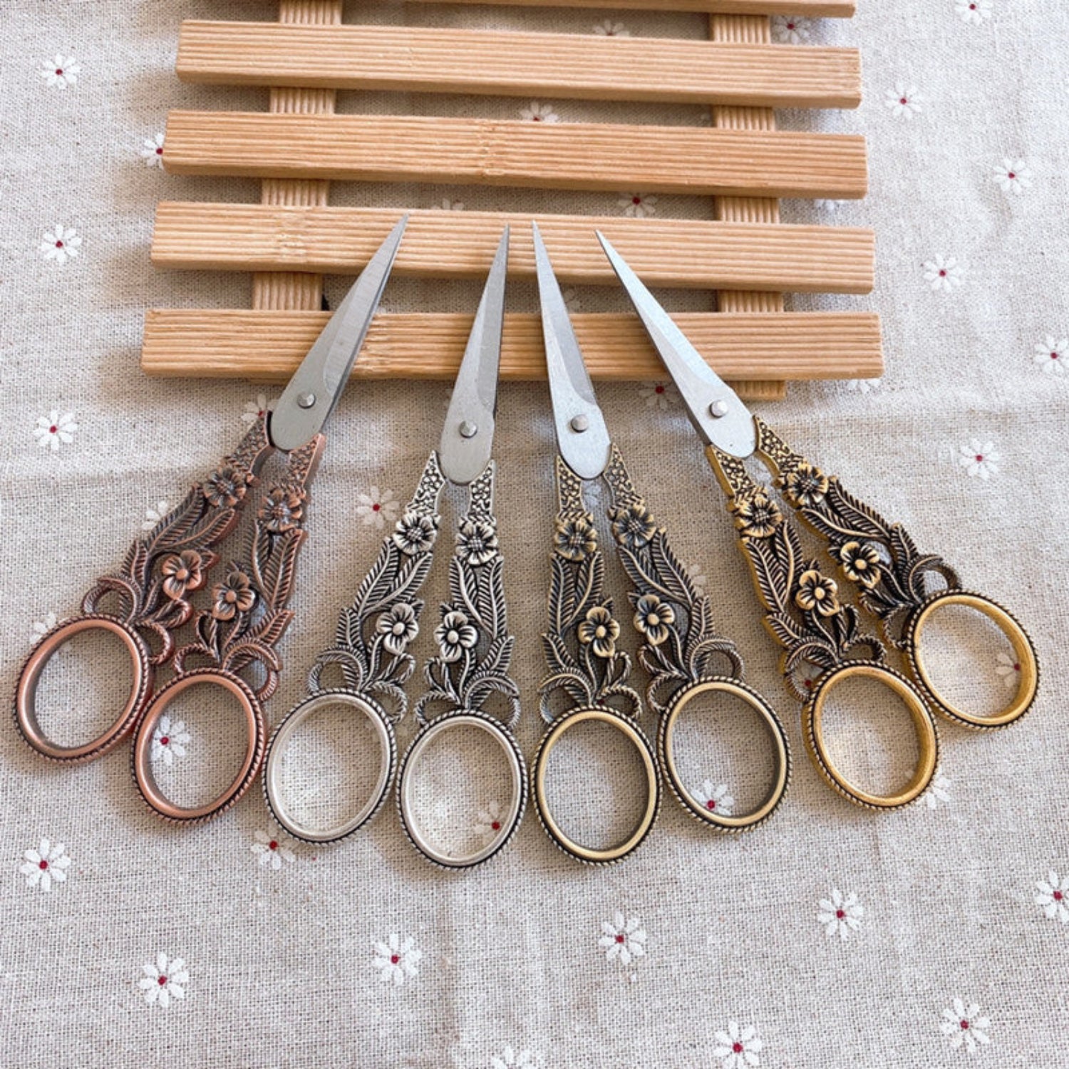 4 pairs of scissors on a wooden tray on white lace background