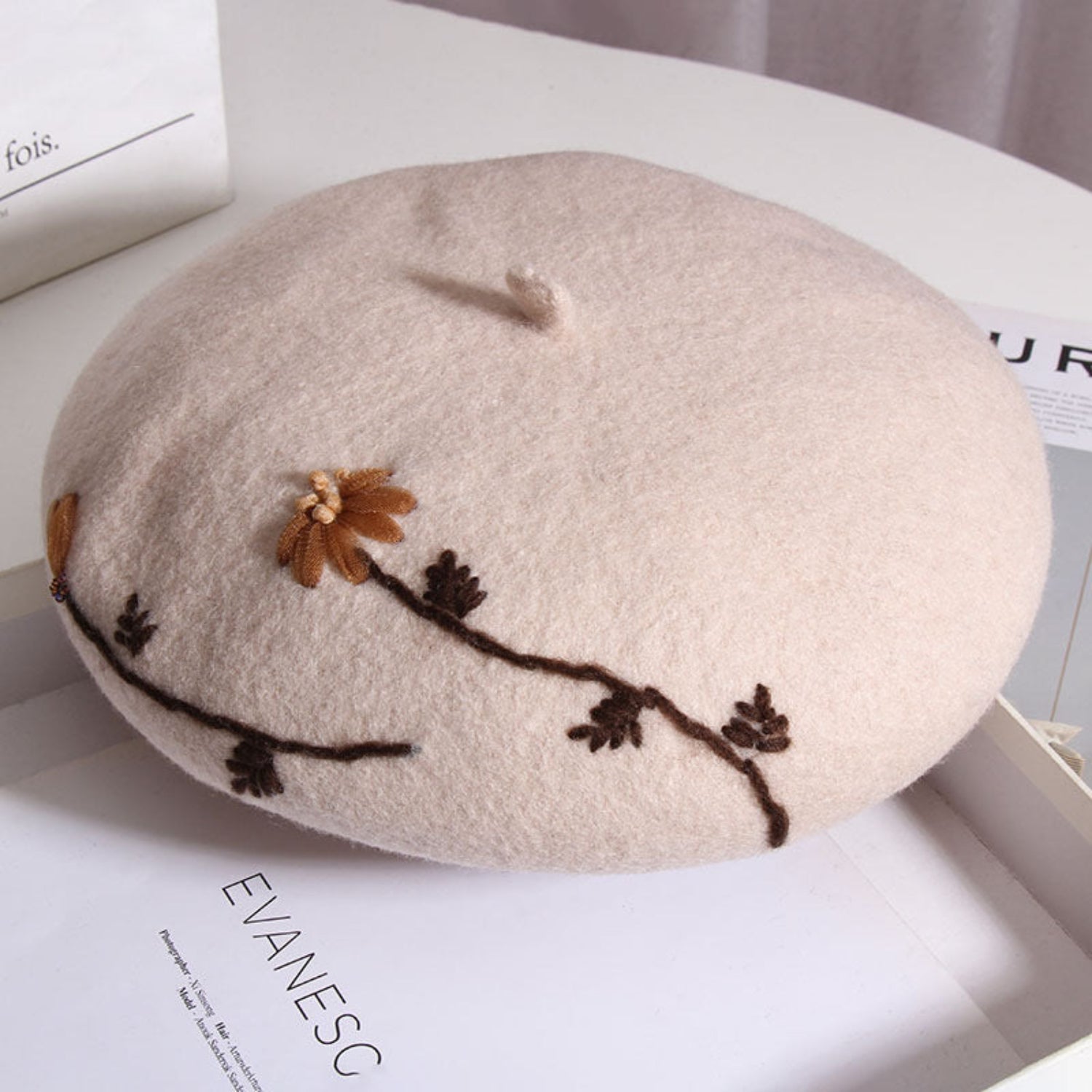 beige daisy embroidered beret on a table