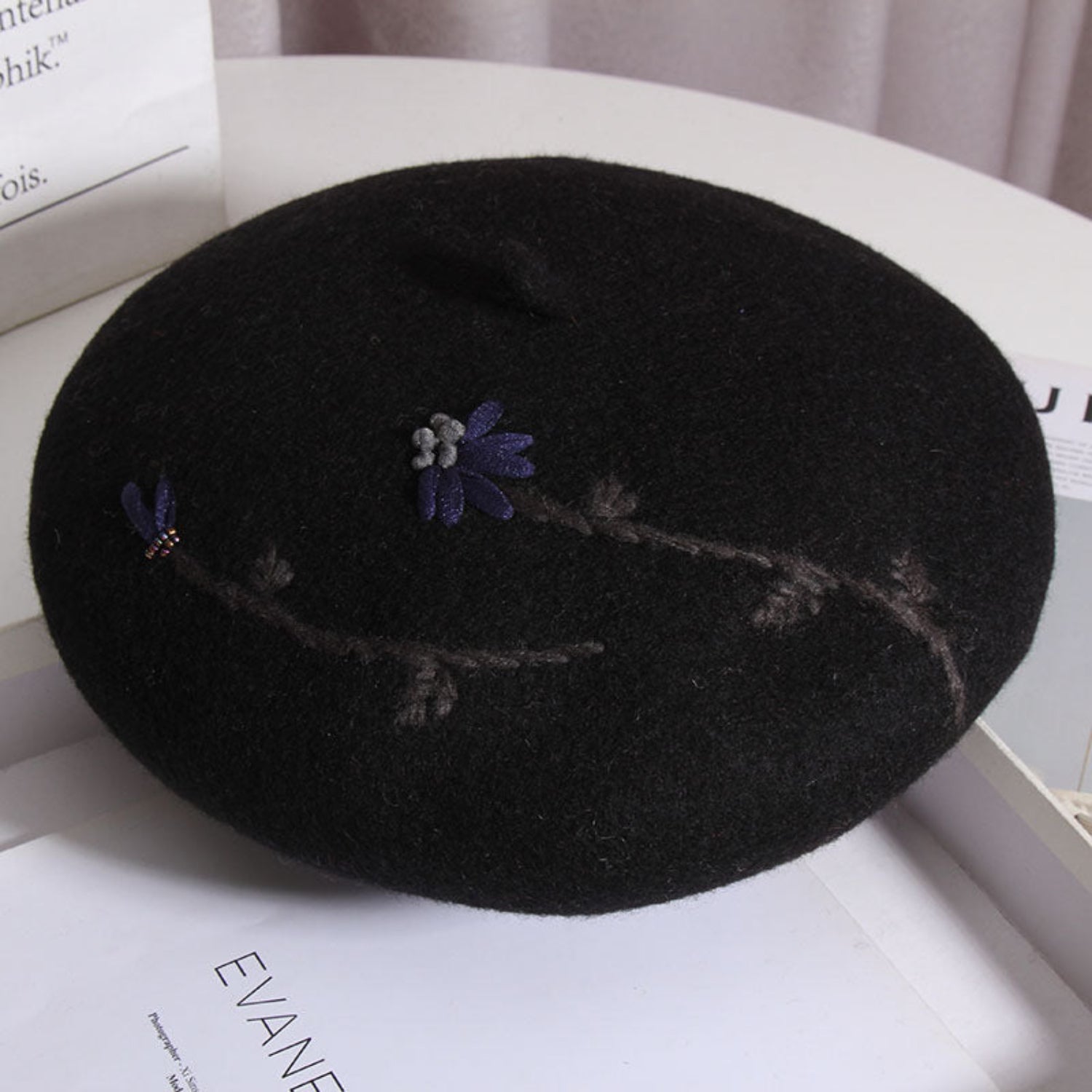 black embroidered daisy beret on a table