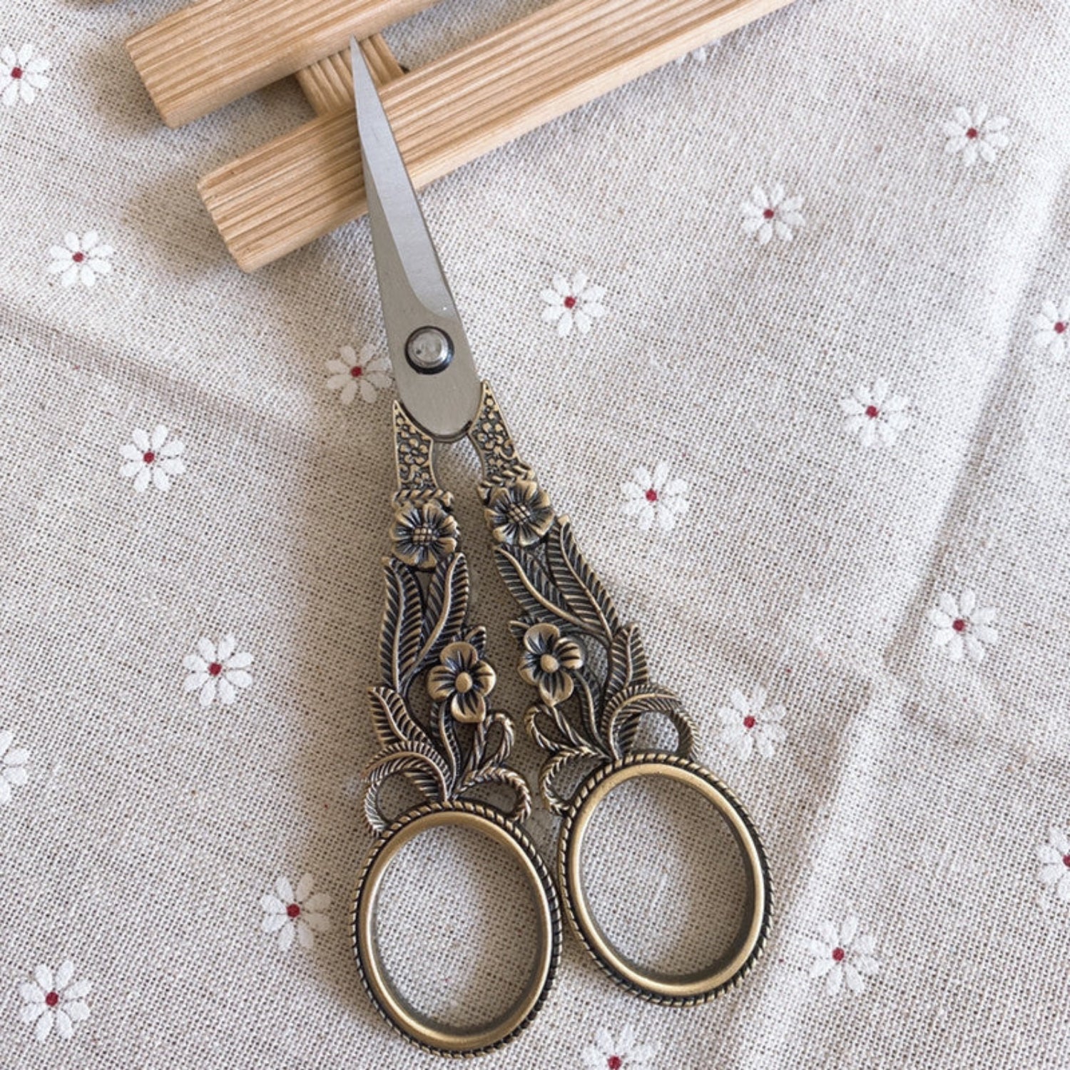 Bronze scissors on wood tray on white flower background