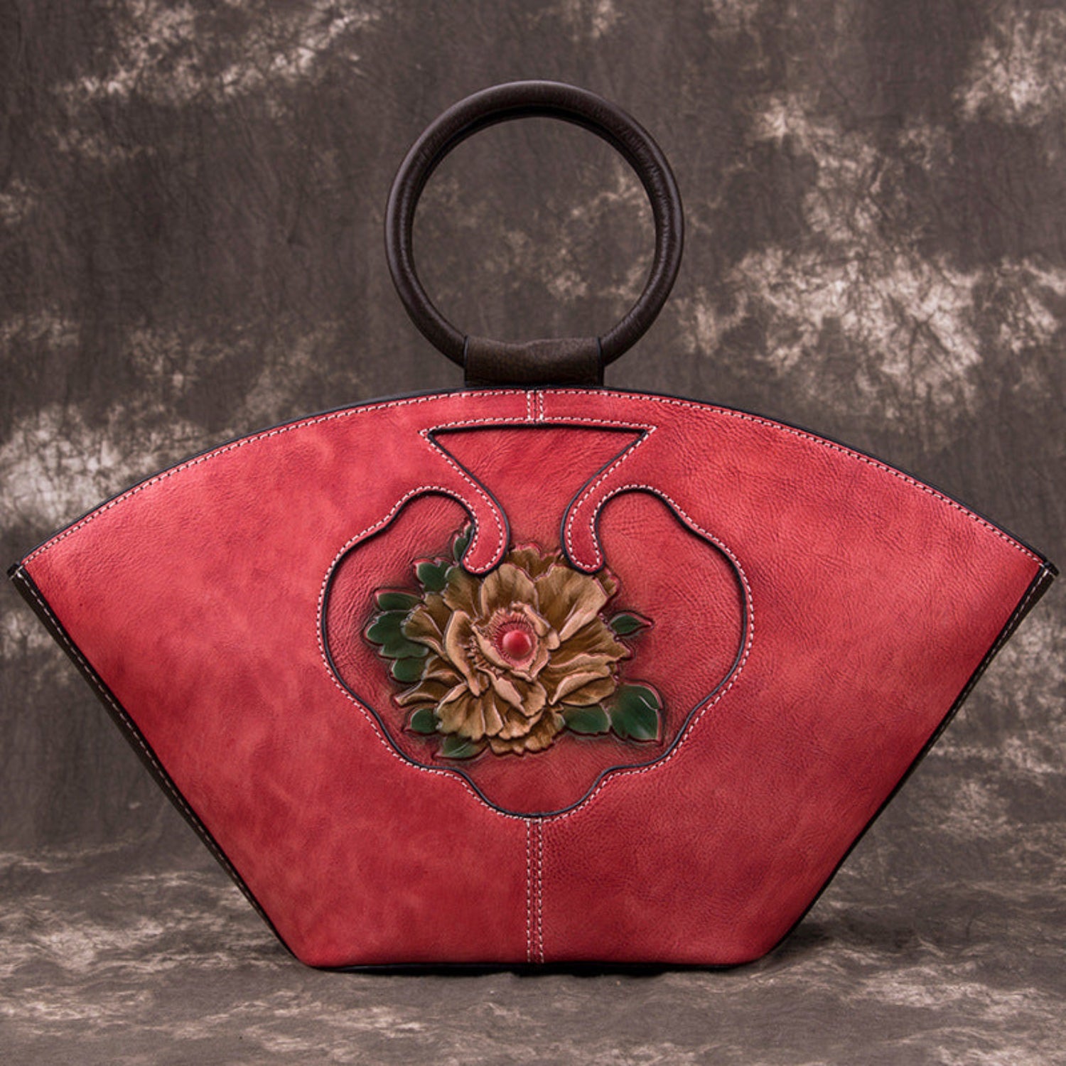 Vintage‑style leather Boston bag with an embossed flower inside a bottle‑shaped motif.