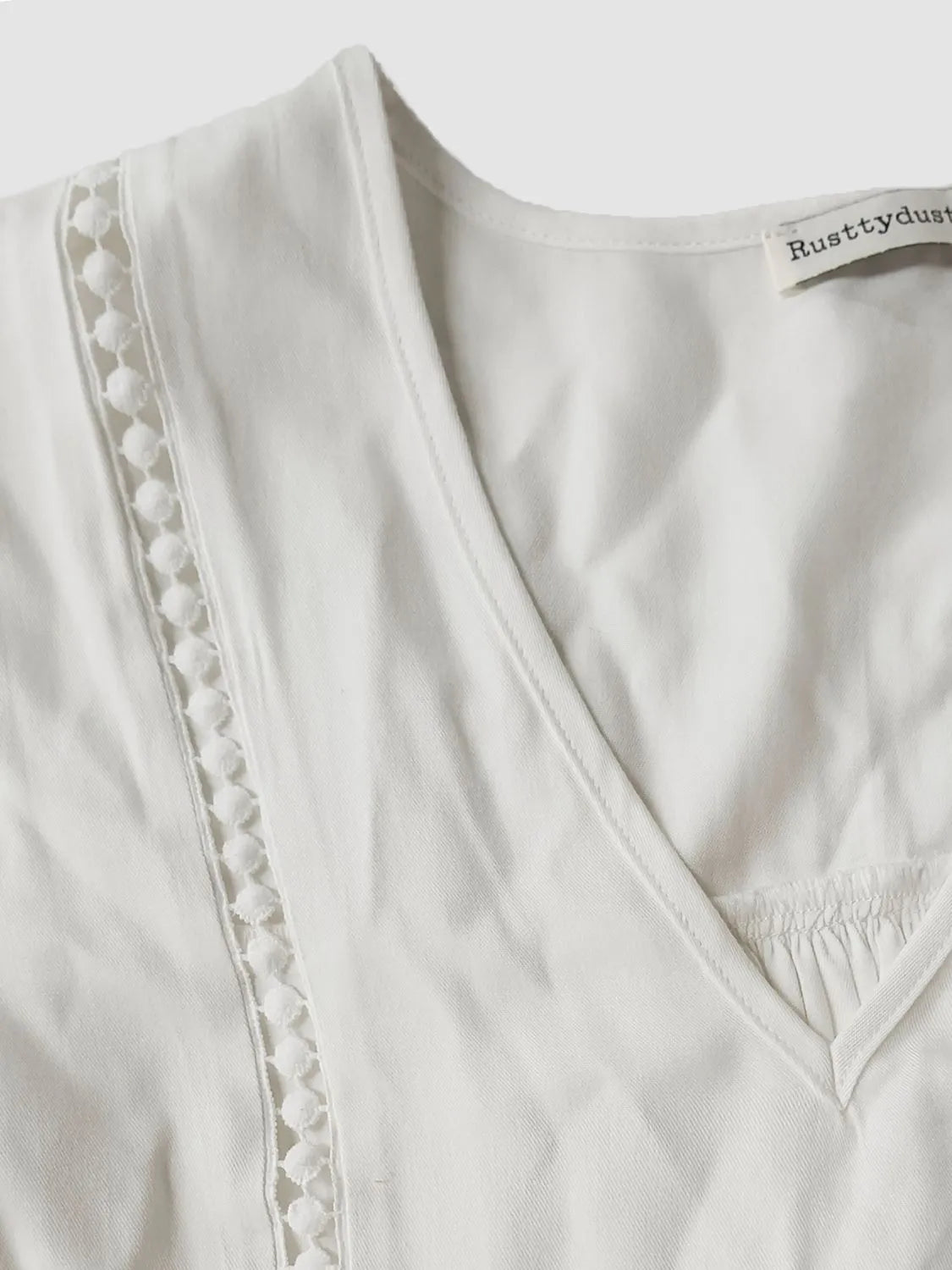 Close‑up of the front of the Enchanted Lace Flounce Sleeve Top showing lace accents, V‑neckline, and ruched detailing.