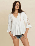 Model wearing the white Enchanted Lace Flounce Sleeve V‑Neck Top showing full front view with lace details and flounce sleeves.