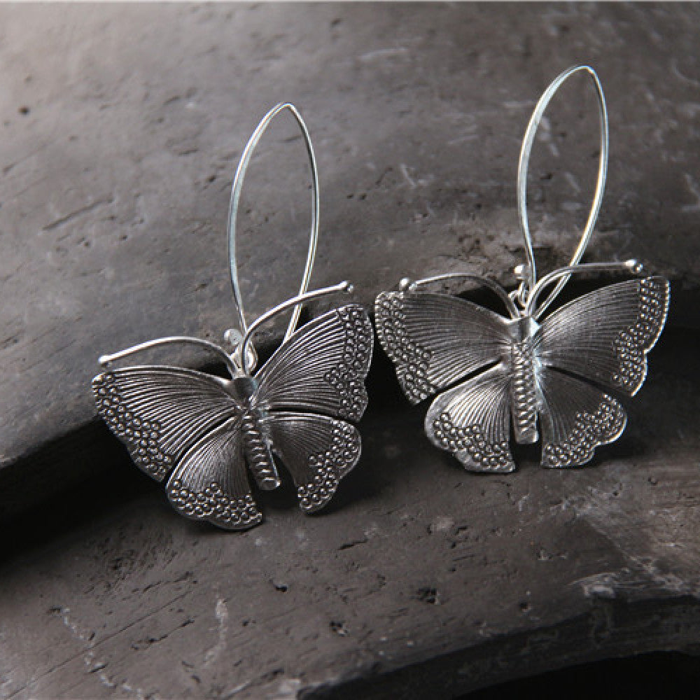 Front view of Sterling silver moth earrings with detailed wings hanging from silver French hook ear wires.