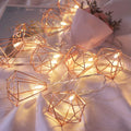 Geometric string lights with warm glow on a soft fabric background