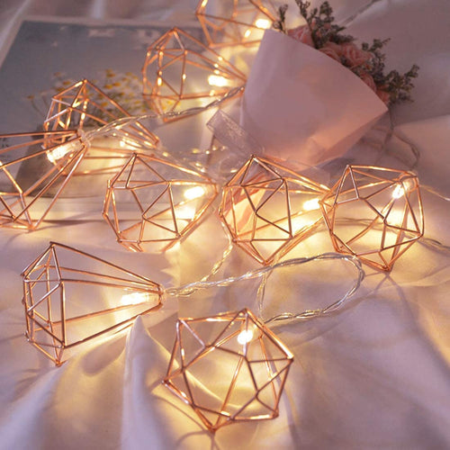 Geometric string lights with warm glow on a soft fabric background