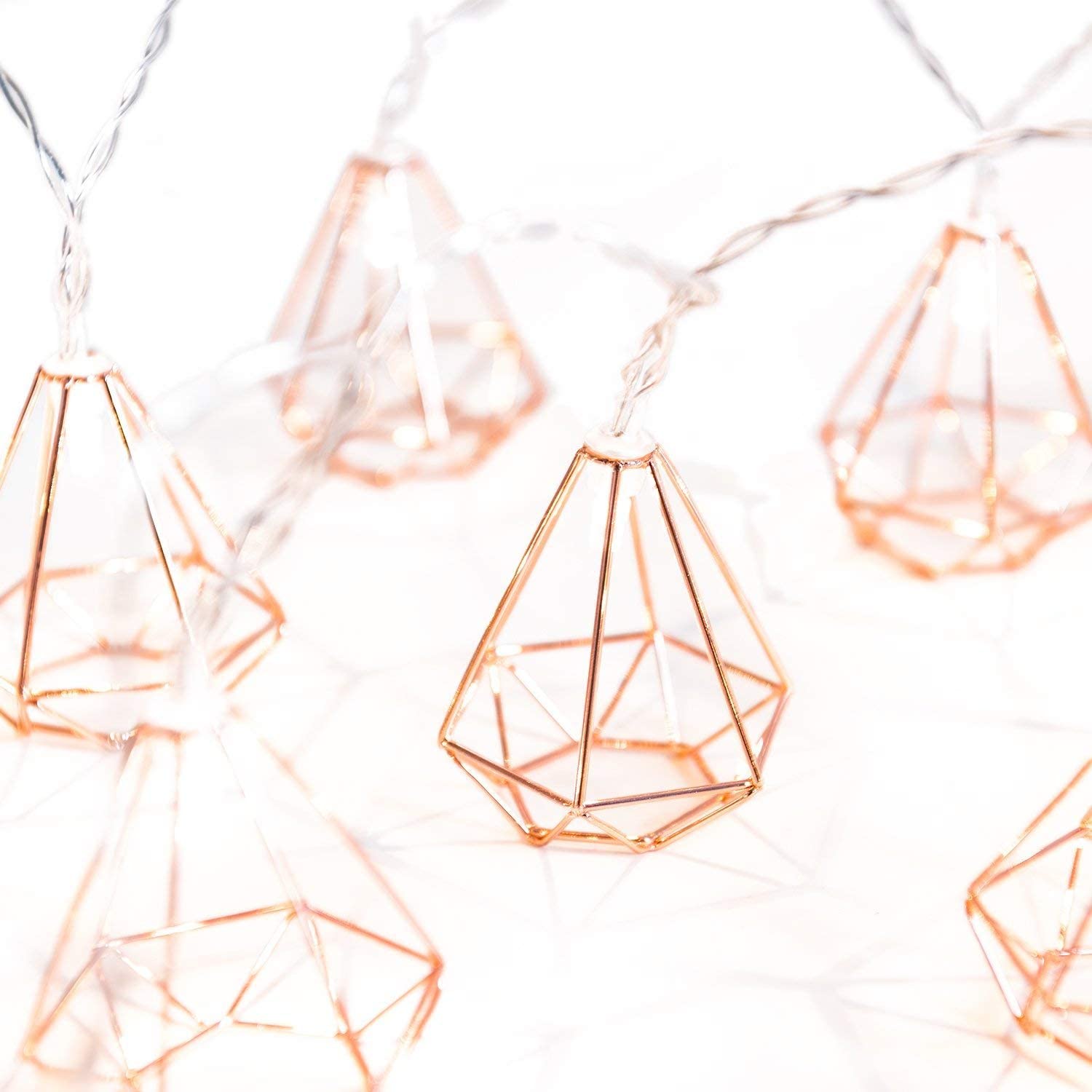 Geometric string lights with rose gold accents on a white background