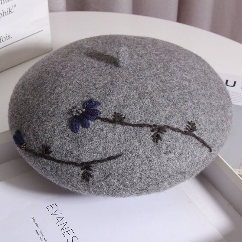 gray daisy embroidered beret on a table