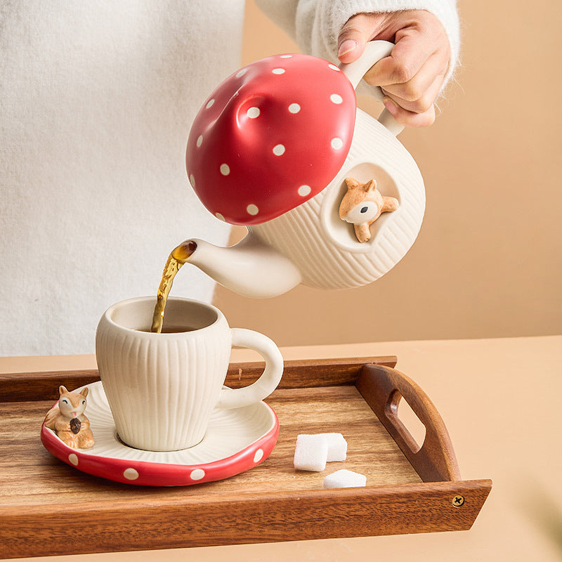 person pouring tea in a cup from a teapot on wood tray
