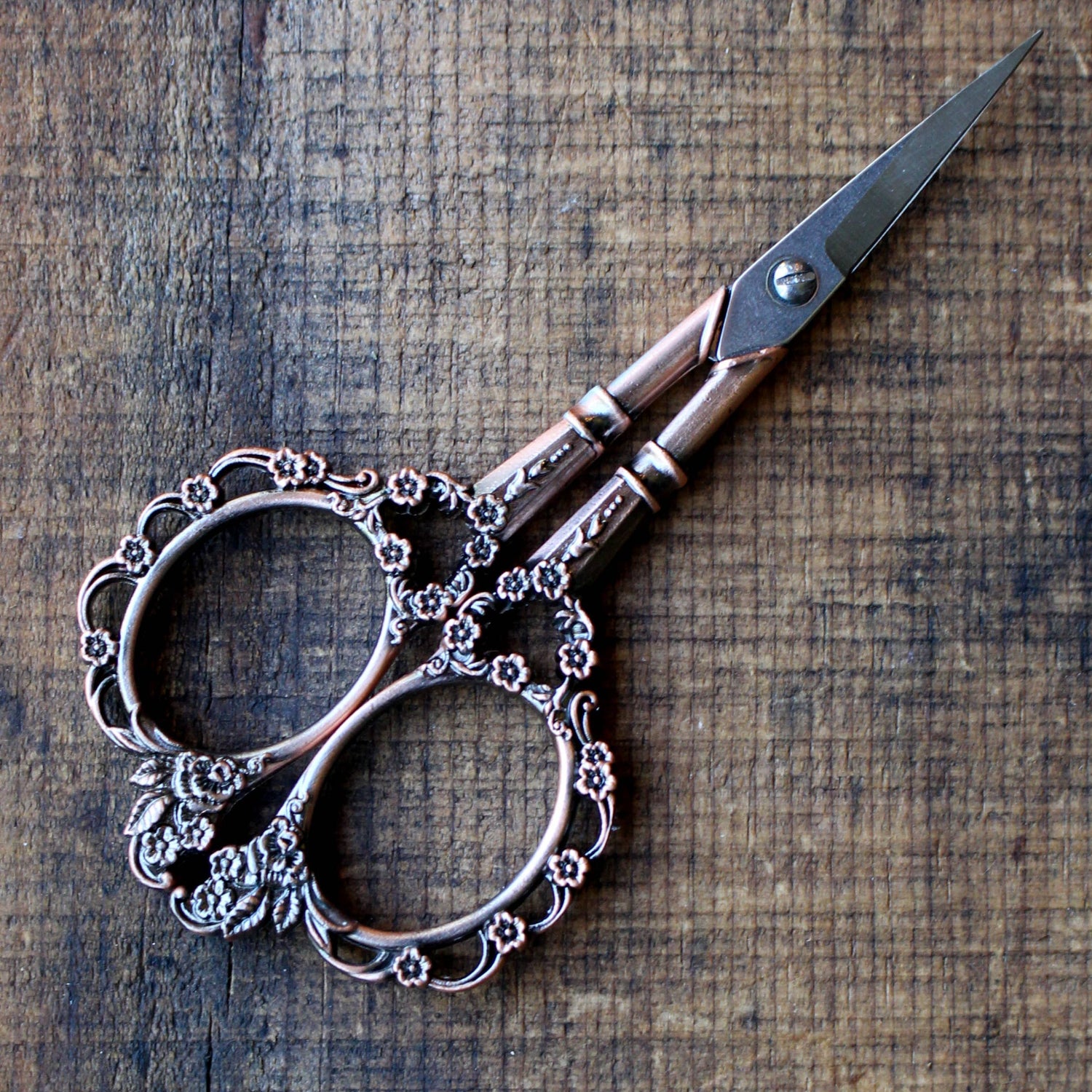 Decorative scissors with intricate design on a wooden surface