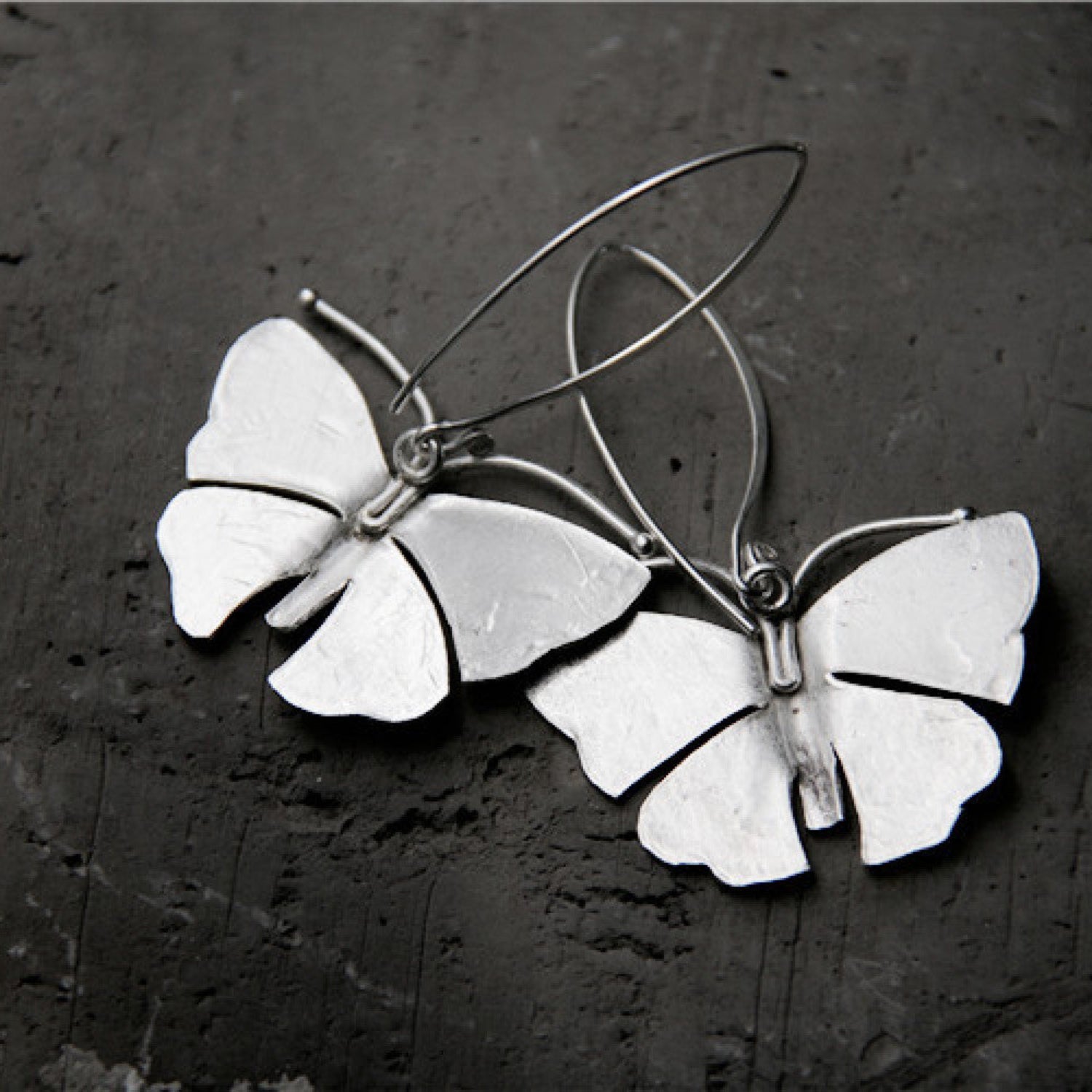 Back view of Sterling silver moth earrings with detailed wings hanging from silver French hook ear wires.