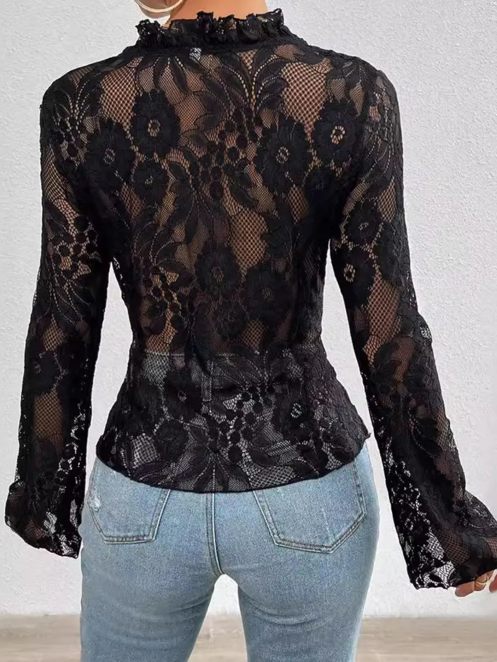Black lace top worn with light blue jeans against a white background