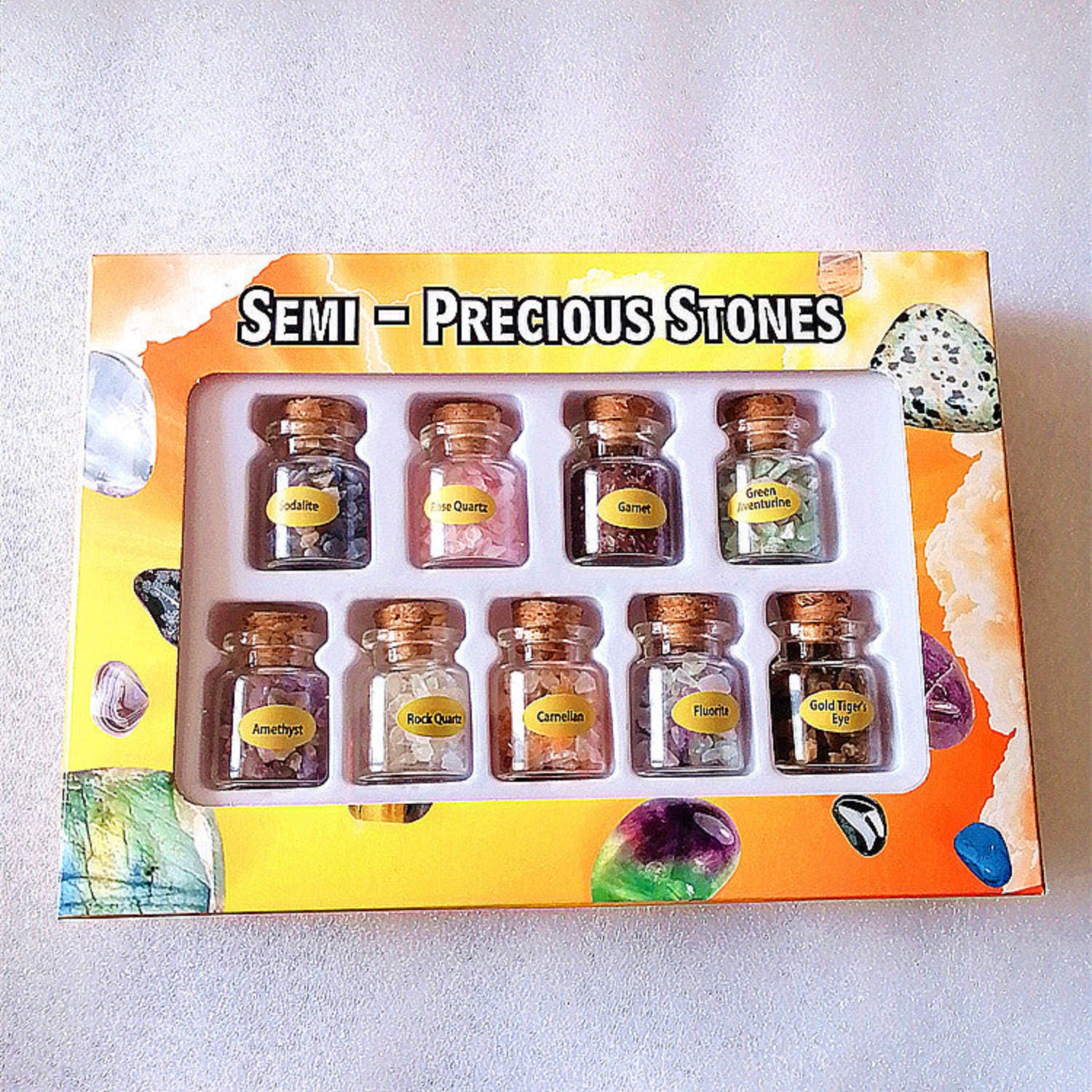 bottles of crushed semi-precious stones in a box on a white background