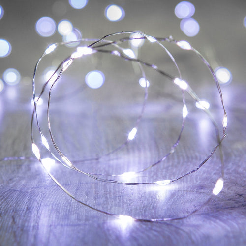 Coiled string of LED lights on a wooden surface with blurred lights in the background