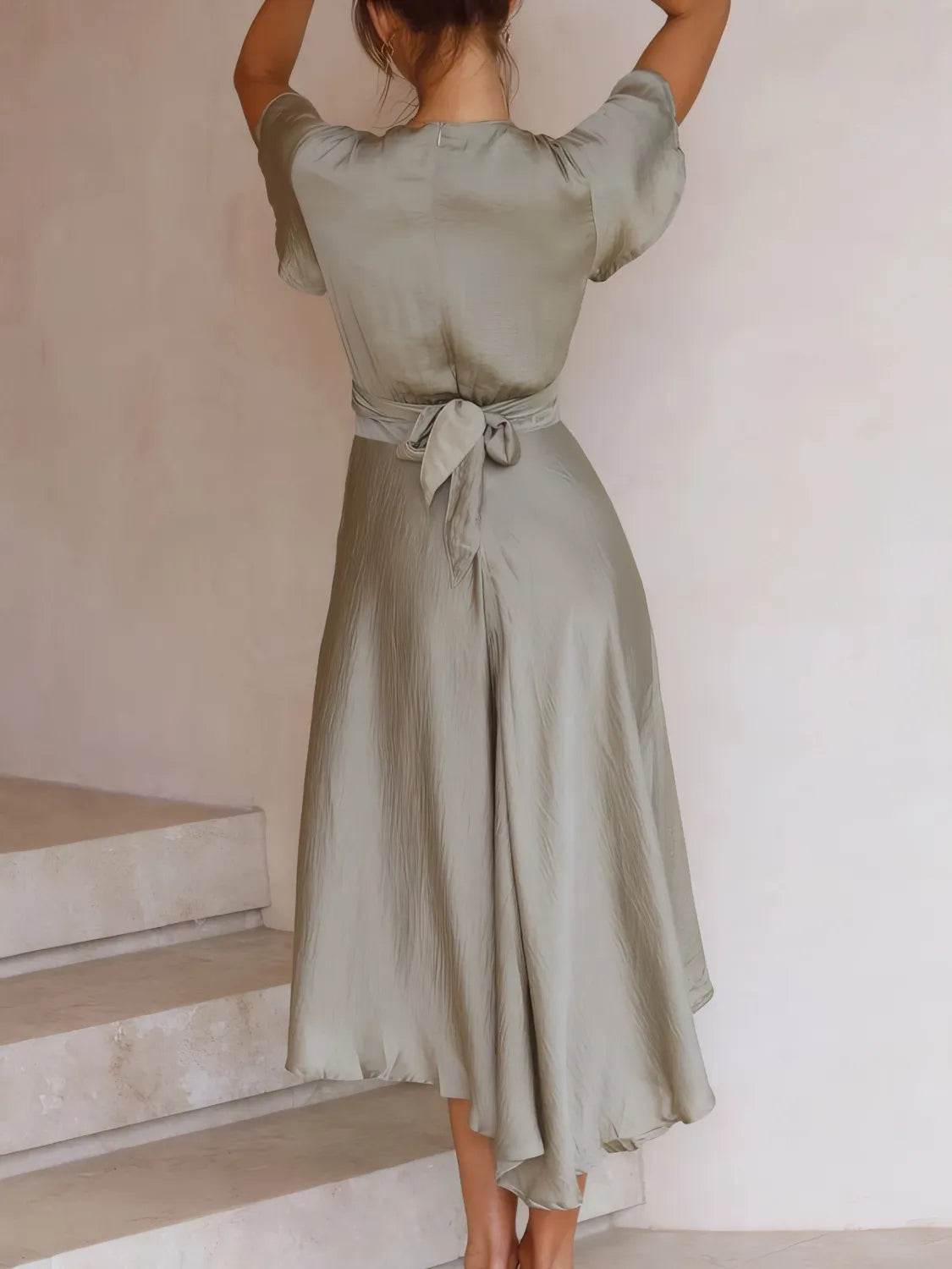 Back view of the sage high‑low plunge dress on the model, showing the crisscross tie‑back and airy movement.