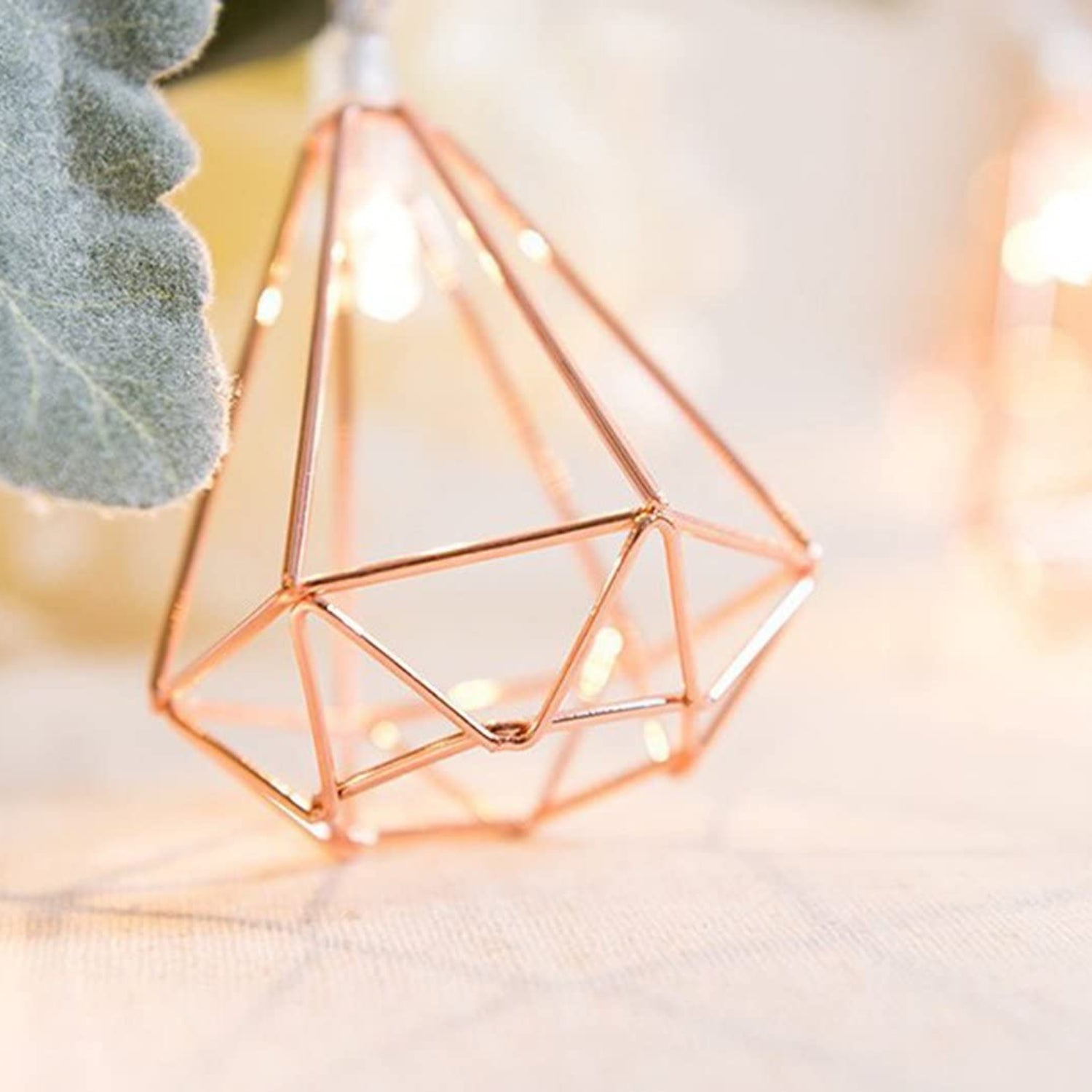 Geometric copper lantern with fairy lights on a soft background
