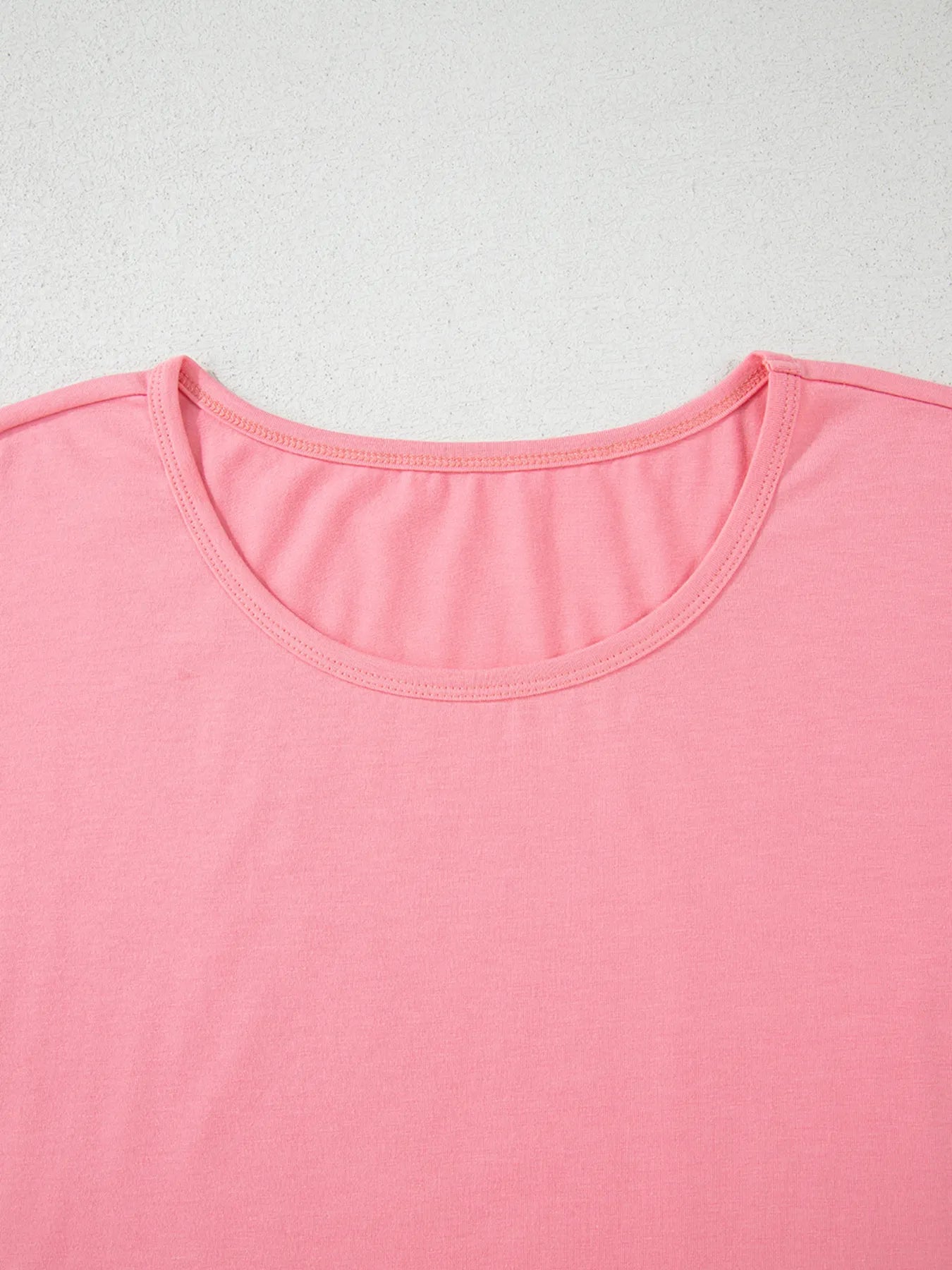 Close‑up of the round neckline on the pale blush ruffle hem T‑shirt, showing the soft fabric texture.